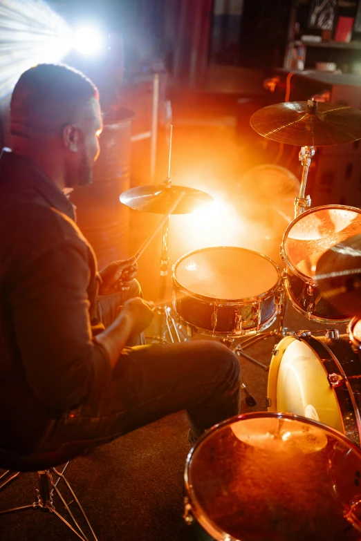 a man sitting in front of a drum set, by Matt Cavotta, shutterstock, warm glow from the lights, band playing instruments, lots of cymbals, medium close-up shot