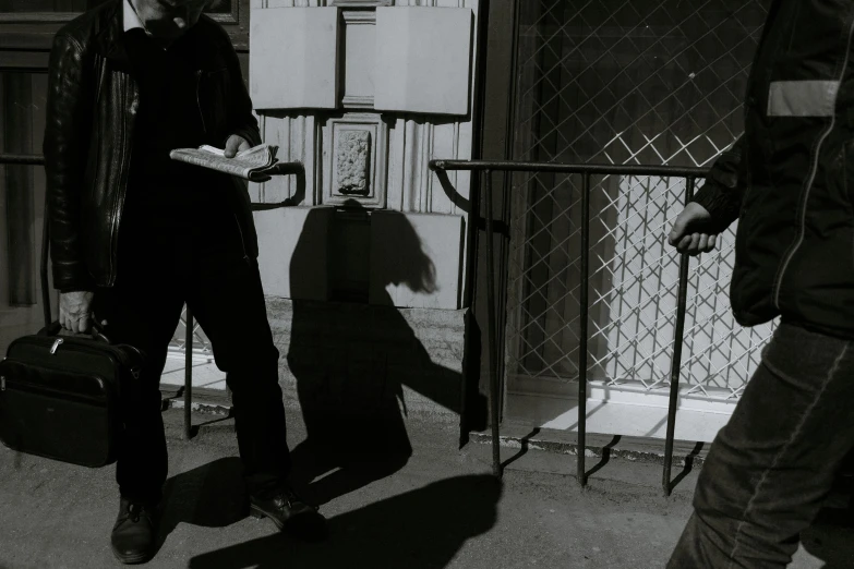 a black and white photo of a man with a suitcase, inspired by Roy DeCarava, realism, big shadows, two figures, delivering mail, ignant