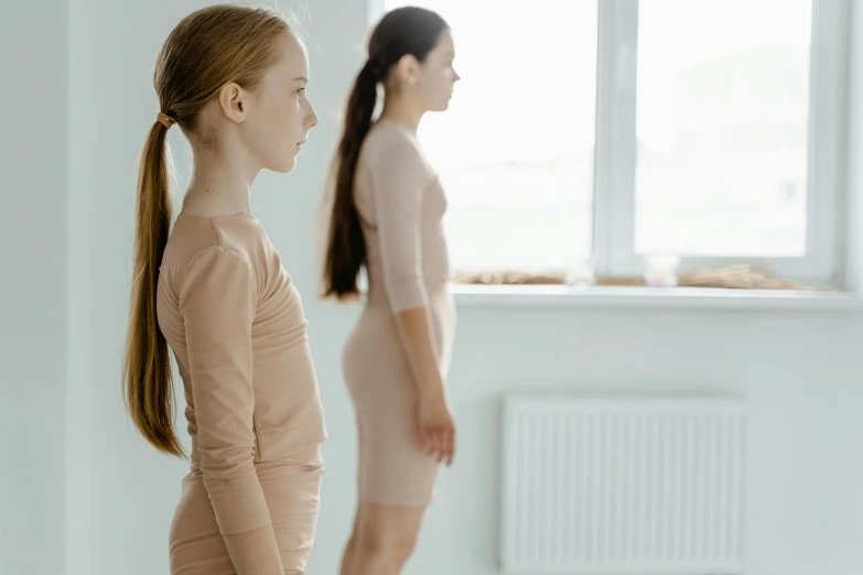 two women standing next to each other in a room, inspired by Vanessa Beecroft, trending on pexels, antipodeans, marjaryasana and bitilasana, teenager girl, princess in foreground, thin face structure