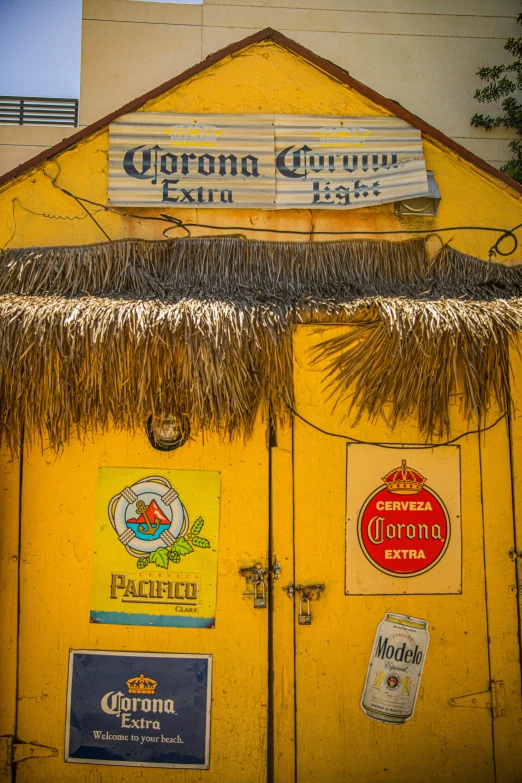 a small yellow building with a thatched roof, graffiti, poster of corona virus, alcohol, caribbean, square