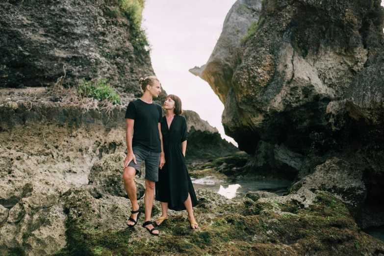 a man and woman standing next to each other on a rocky beach, pexels contest winner, renaissance, new zeeland, casual black clothing, avatar image, rock arches