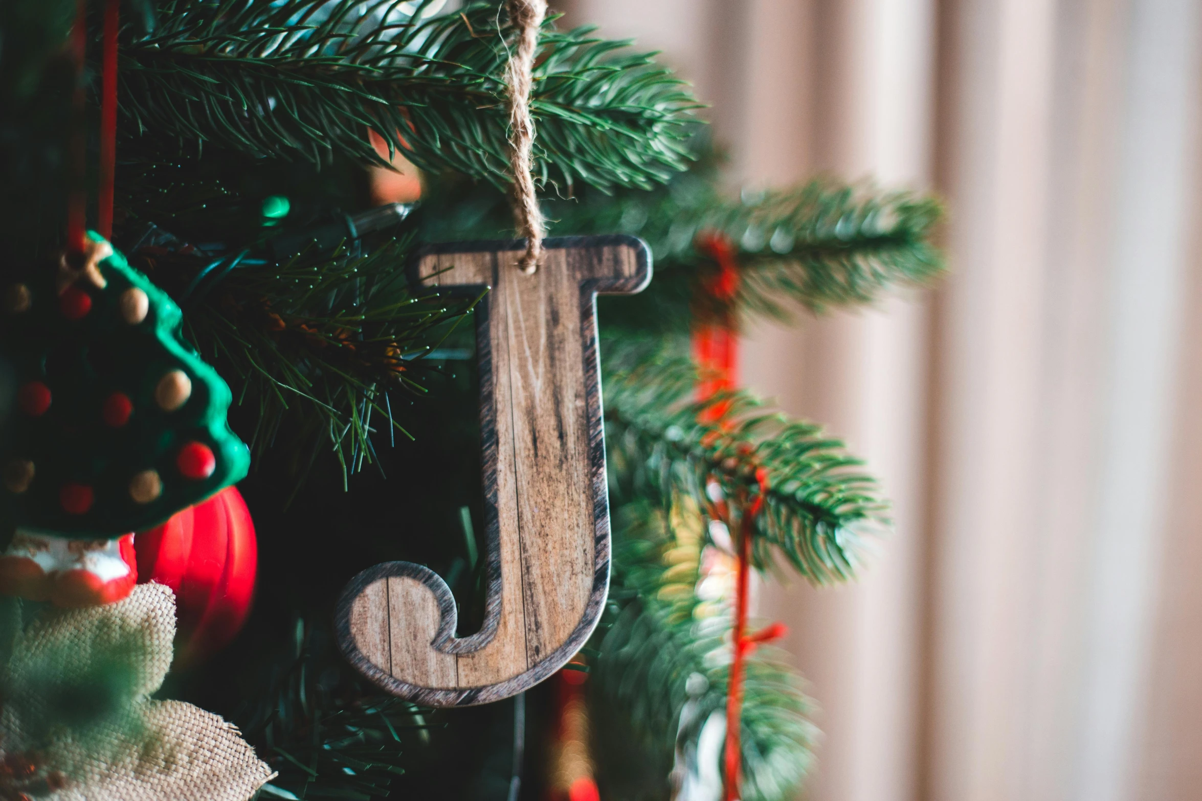 a close up of a christmas tree with ornaments, by Julia Pishtar, pexels, detailed letters, a wooden, j. h. williams iii, organic ornament