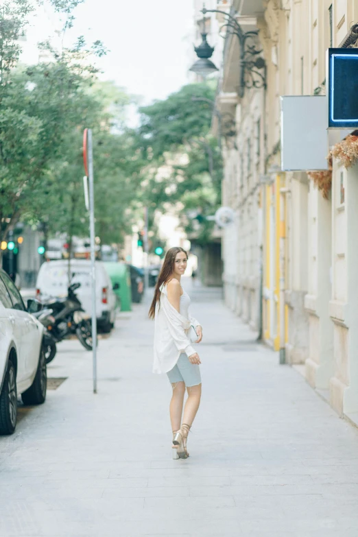 a woman walking down a street next to parked cars, a picture, wearing white skirt, budapest street background, brunette woman, 2019 trending photo