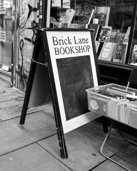 a black and white photo of a book shop, by David Allan, fine art, brick, sign, lane brown, art stand