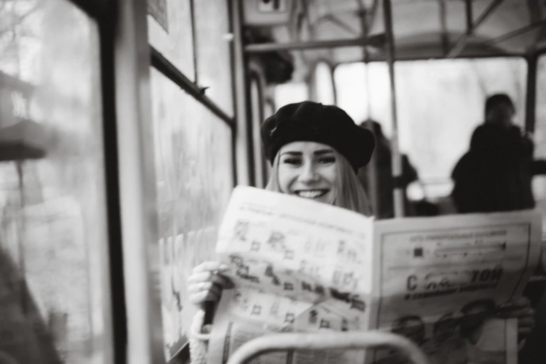 a woman sitting on a bus reading a newspaper, a black and white photo, by Emma Andijewska, pexels contest winner, wearing a beret, cute smile, portrait of kim petras, instagram post