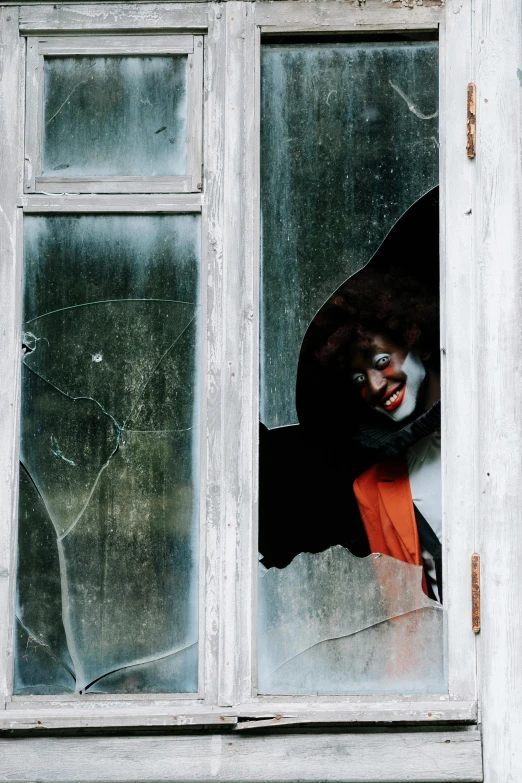 a creepy clown looking out of a broken window, by Attila Meszlenyi, pexels contest winner, cheeky devil, low quality photo, sneaking, album cover