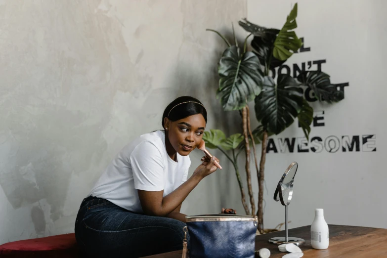 a woman sitting on top of a wooden table, putting makeup on, curated collections, holding a leather purse, avatar image