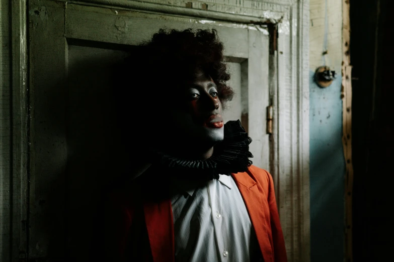 a man dressed as a clown standing in front of a door, a portrait, inspired by Gordon Parks, pexels contest winner, black arts movement, monia merlo, with afro, miranda meeks, halloween