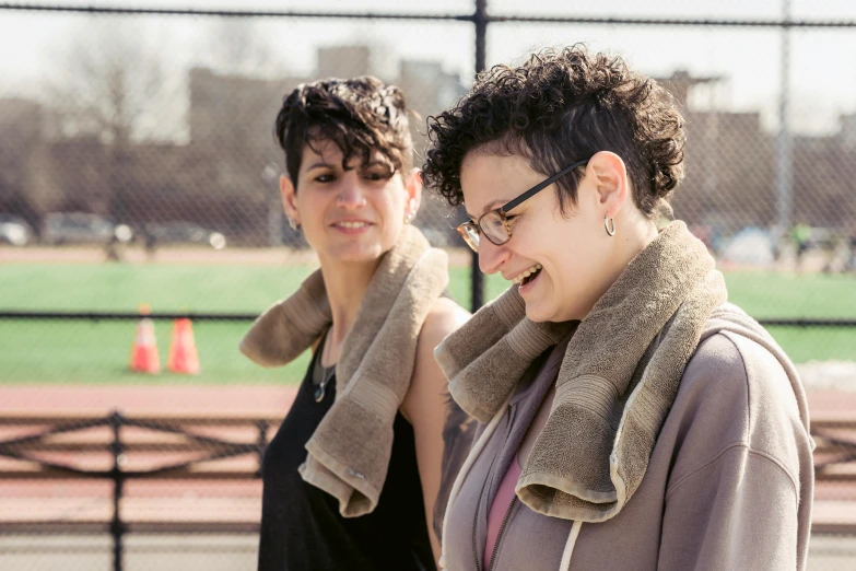 a couple of women standing next to each other, a portrait, by Nina Hamnett, on a soccer field, fluffy neck, yael shelbia, looking to the side off camera