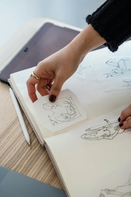 a woman is drawing on a piece of paper, a drawing, trending on pexels, process art, comic book thick outline, behance lemanoosh, centered design, top down drawing