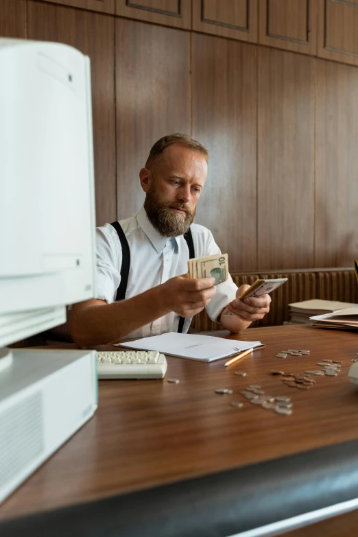 a man sitting at a desk with money in front of him, pexels contest winner, hipster dad, ( ( mads berg ) ), portrait of hide the pain harold, big budget movie scene