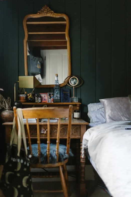 a bedroom with a desk a chair and a mirror, a portrait, unsplash, dark green, cottage, conde nast traveler photo, wood paneling