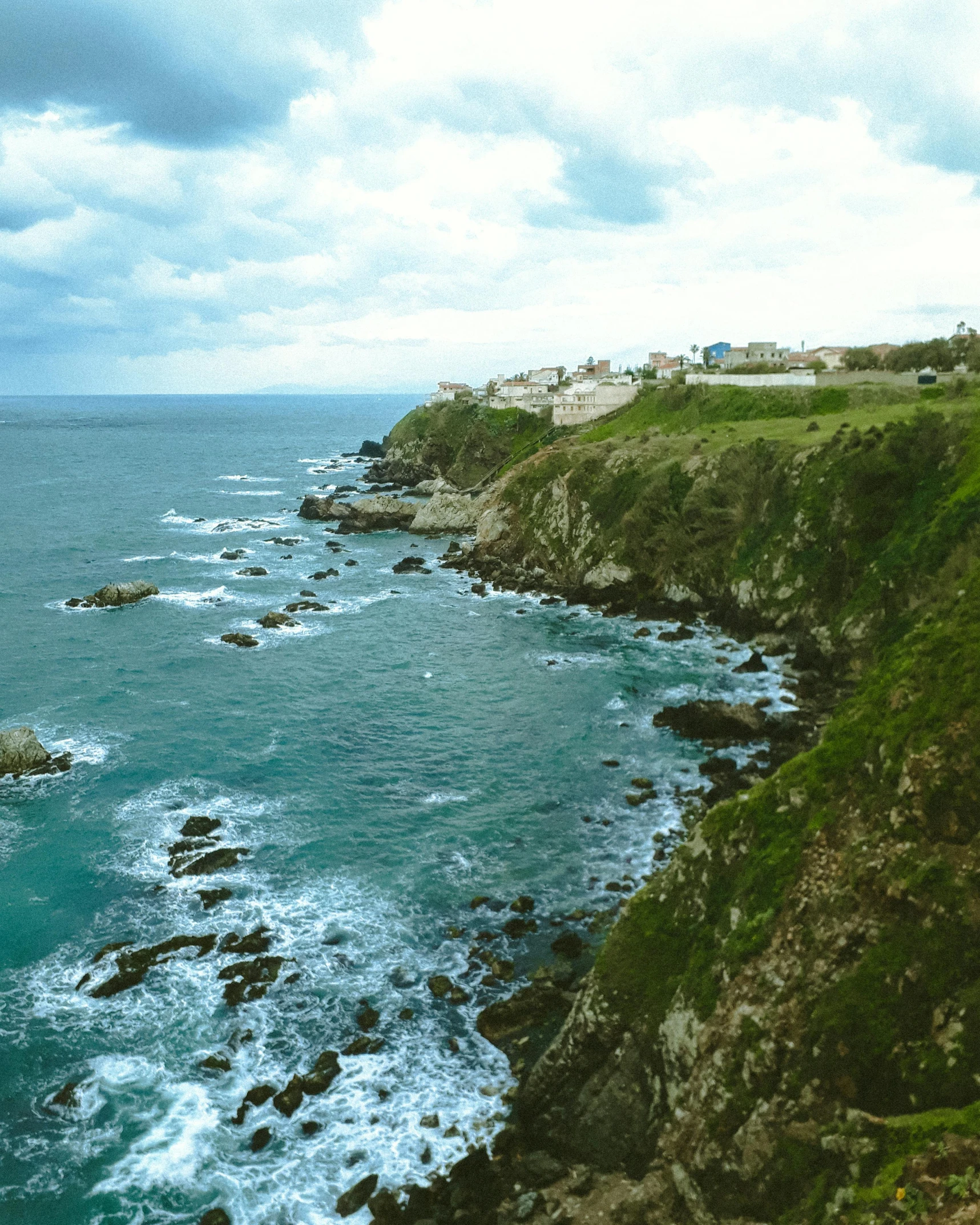 a large body of water next to a lush green hillside, pexels contest winner, sea spray, cliffside town, profile image, instagram photo