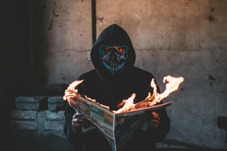 a person in a hoodie reading a book with fire coming out of it, pexels contest winner, graffiti, robot ghost mask, avatar image, newspaper photography, all black cyberpunk clothes