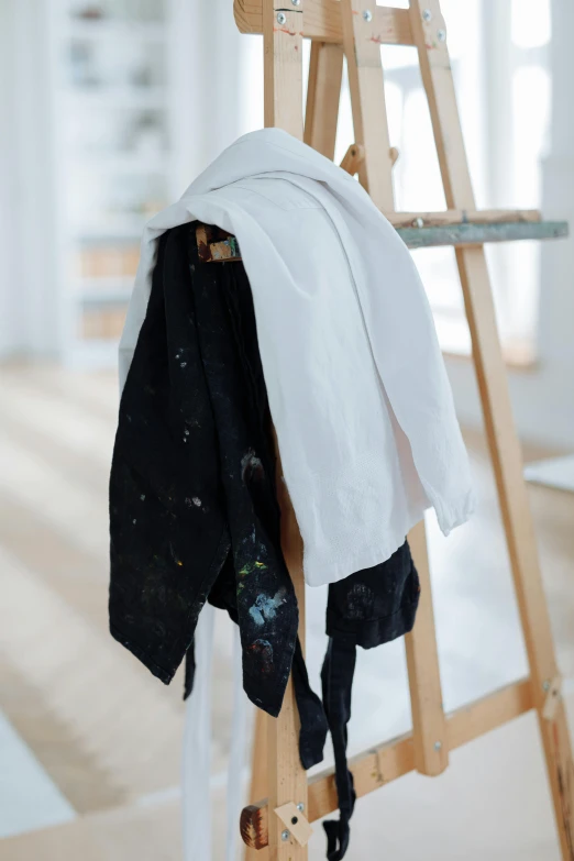 a ladder with clothes hanging on it in a room, by Nina Hamnett, unsplash, white apron, black jacket, digitally painted, with a white