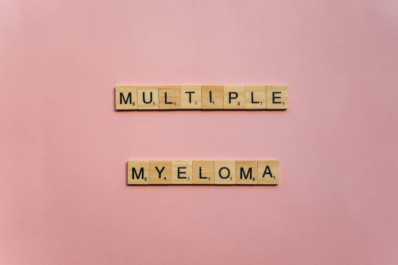 scrabble tiles spelling multiple myeloma on a pink background, by Mym Tuma, shutterstock, international typographic style, mycelium, meme template, bilateral symmetry, on a canva