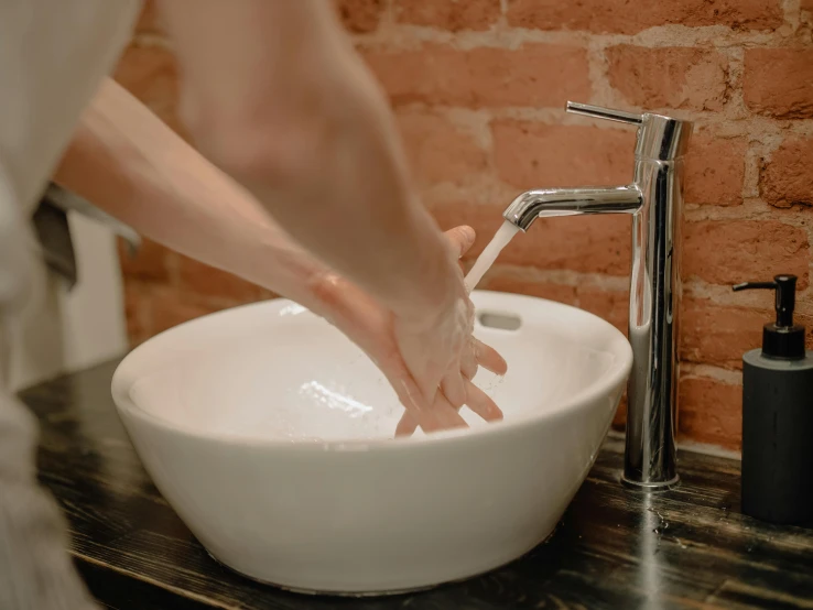 a person washing their hands in a bathroom sink, a marble sculpture, by Emma Andijewska, pexels contest winner, ginger, plated arm, fully functional, performing