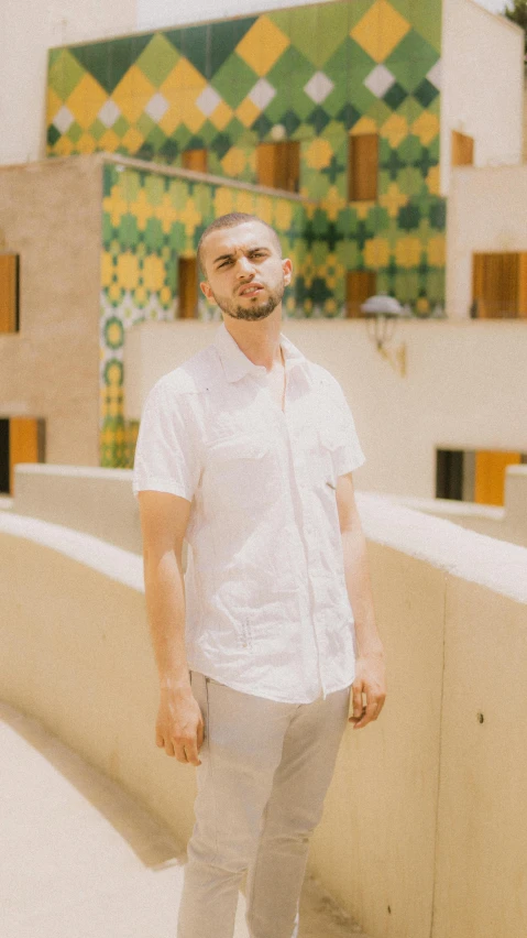 a man standing in front of a building, wearing a white shirt, rex orange county, moroccan, solid background