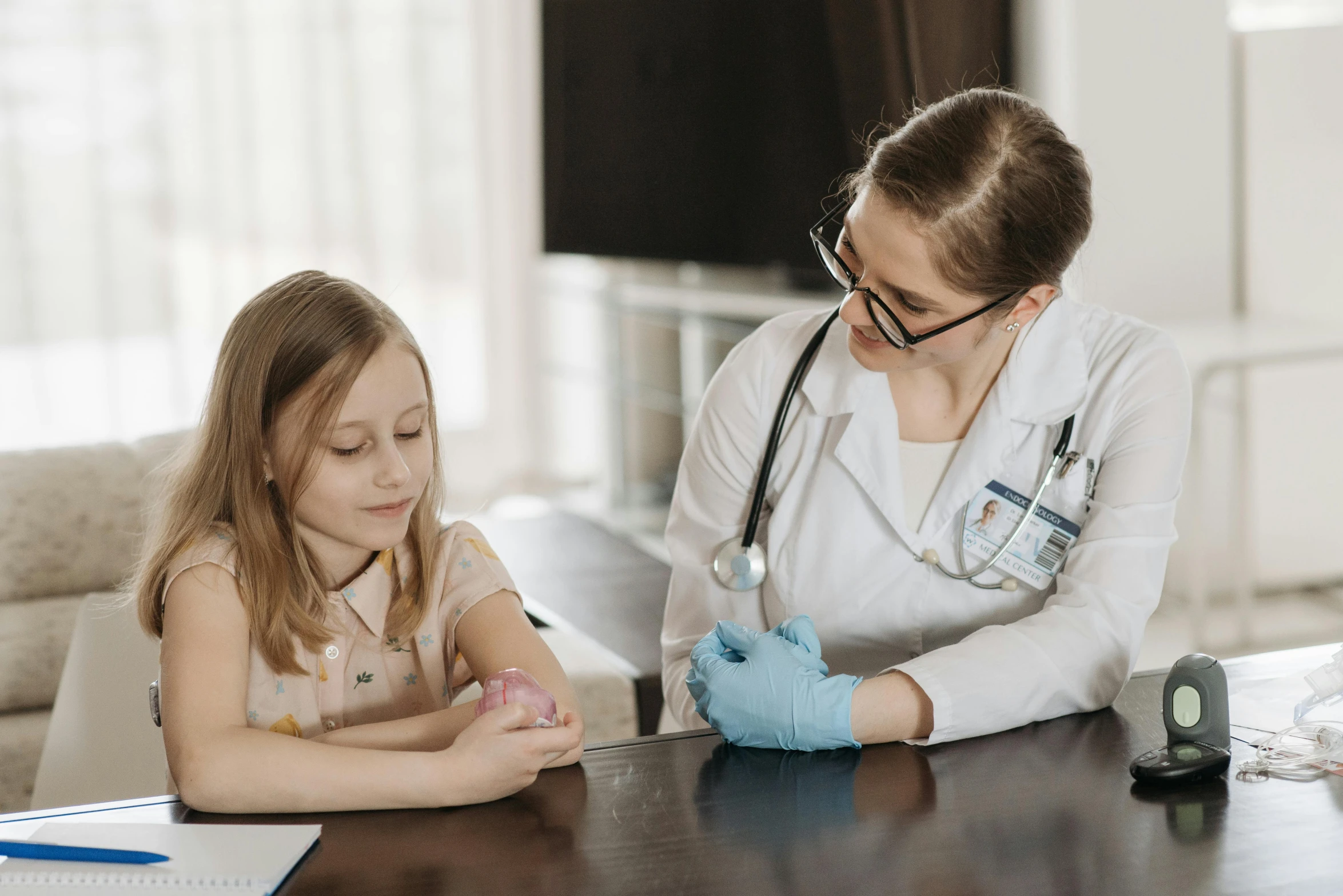 a little girl sitting at a table with a doctor, by Emma Andijewska, pexels contest winner, black bandage on arms, 15081959 21121991 01012000 4k, holding syringe, gif