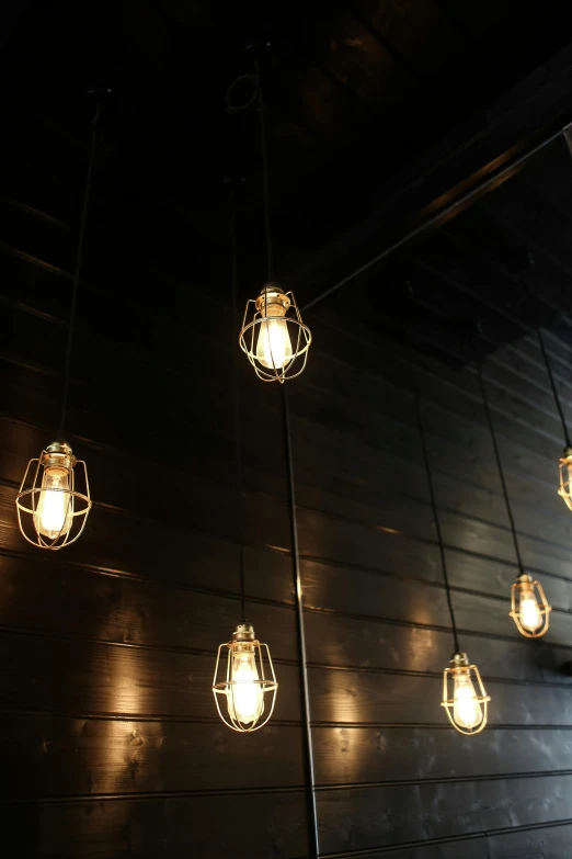 a bunch of light bulbs hanging from the ceiling, dark lighting, brightly lit - style atmosphere