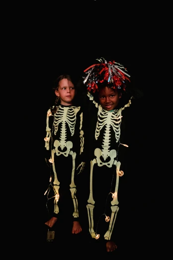 two children in skeleton costumes standing next to each other, by Ellen Gallagher, psychedelic photoluminescent, 2000s, dark-skinned, cardboard