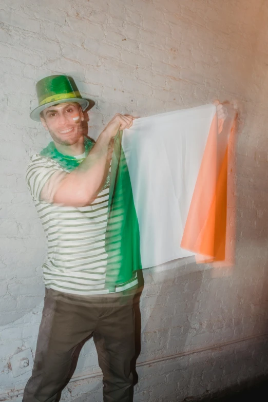 a man standing in front of a wall holding an irish flag, a photo, trending on reddit, renaissance, wearing translucent sheet, circa 2 0 0 8, the rad hatter, vacation photo