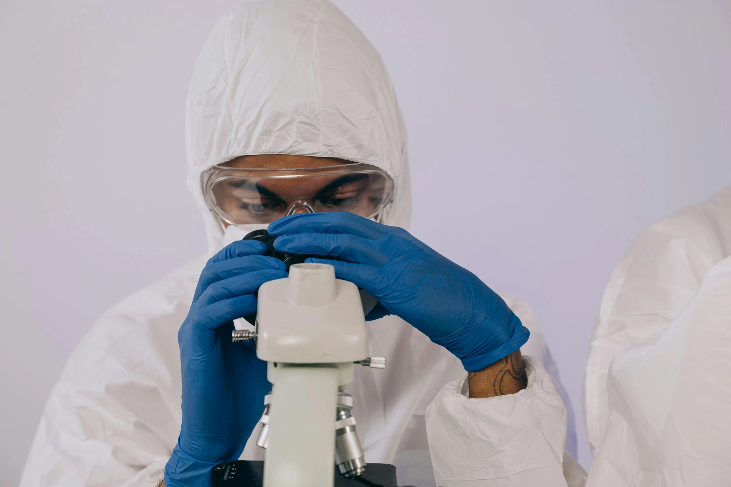 a man in a lab coat looking through a microscope, pexels contest winner, staff wearing hazmat suits, avatar image, wearing a hood, mid shot photo