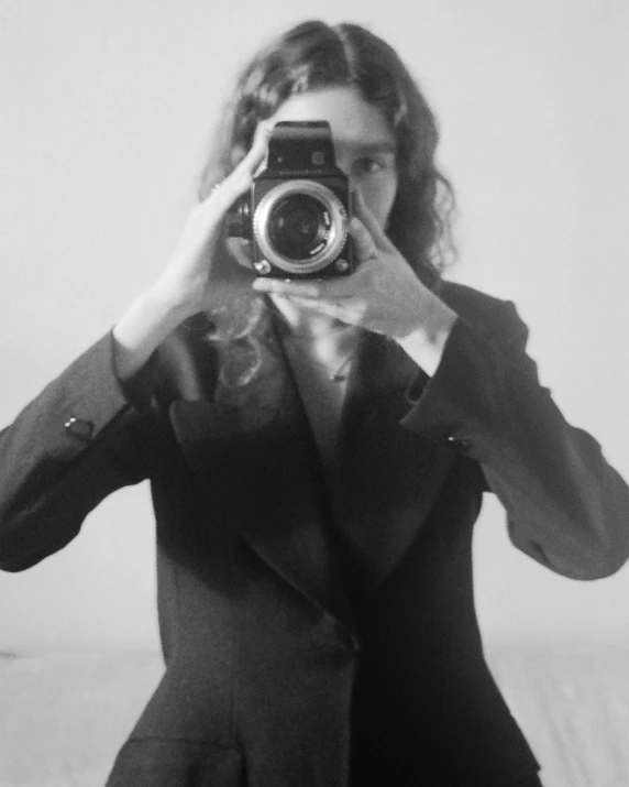 a woman taking a picture with a camera, a black and white photo, inspired by Annie Leibovitz, tumblr, surrealism, hozier, moody : : wes anderson, girl in a suit, bruce kaiser