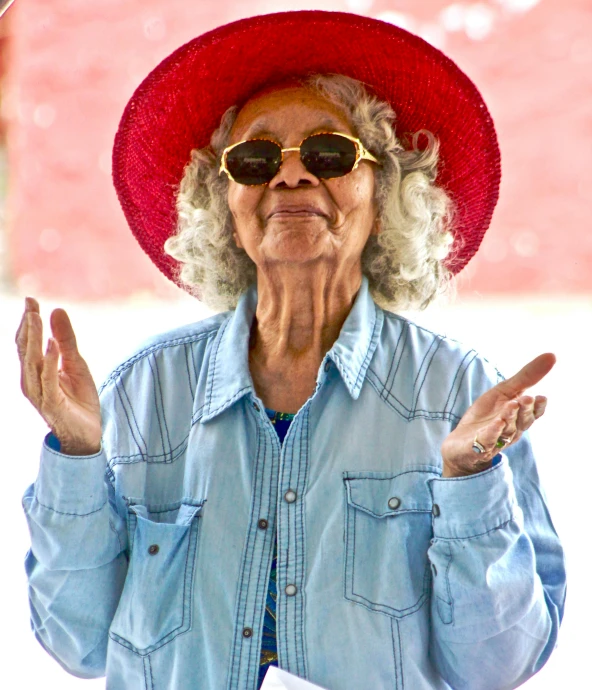 an older woman wearing a red hat and sunglasses, by Betye Saar, pexels, pop art, shrugging, mexico, portrait image, tourist photo