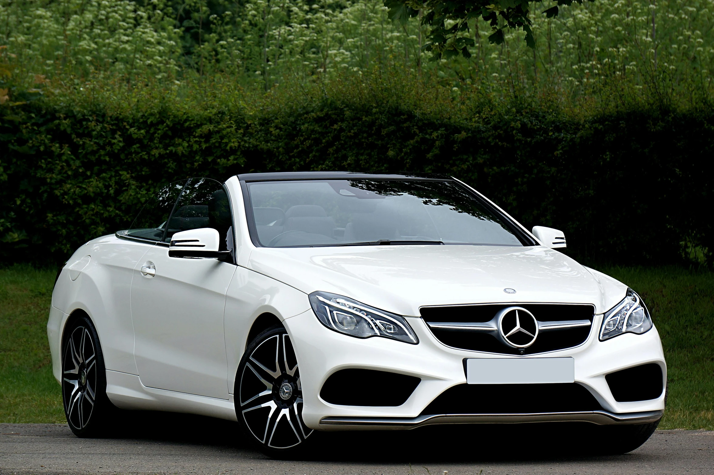 a white car is parked on the side of the road, mercedez benz, soft top, white on black, front facing