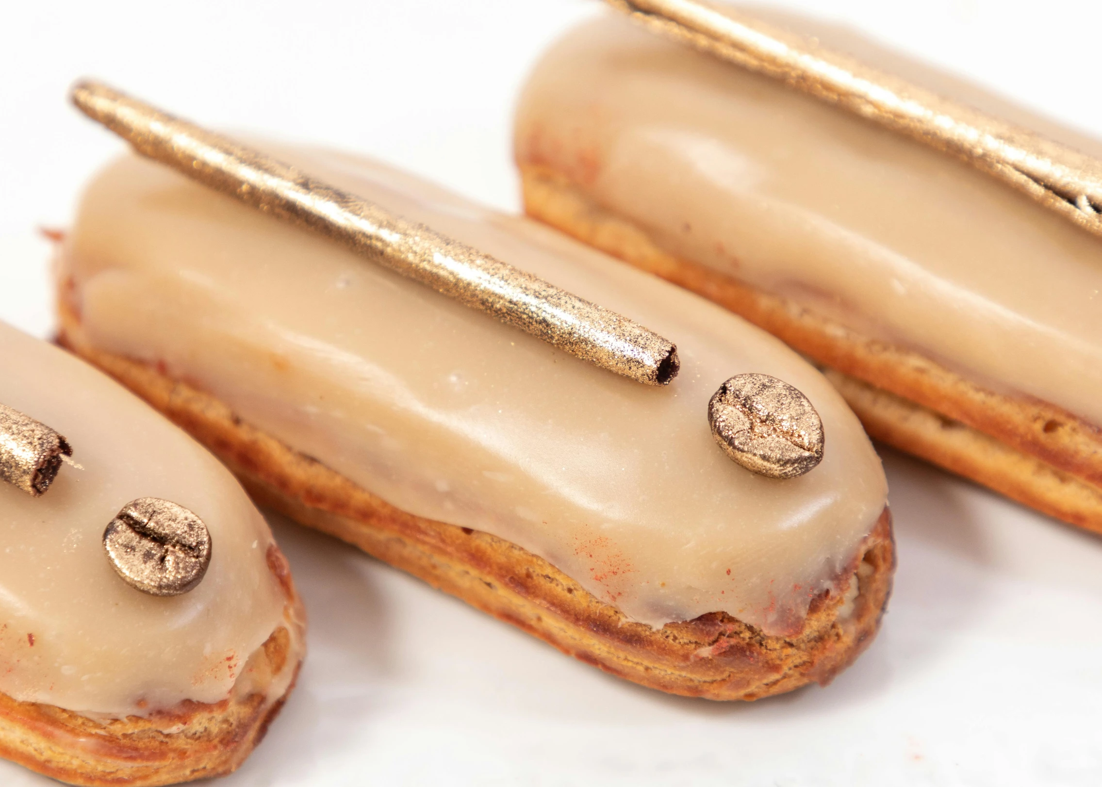 three donuts sitting next to each other on a white surface, inspired by Richmond Barthé, art nouveau, long thick shiny gold beak, thin gold details, bronze poli, pastry