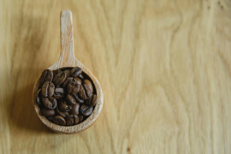 a wooden spoon filled with coffee beans on top of a wooden table, detailed product image, fan favorite, round-cropped, album photo