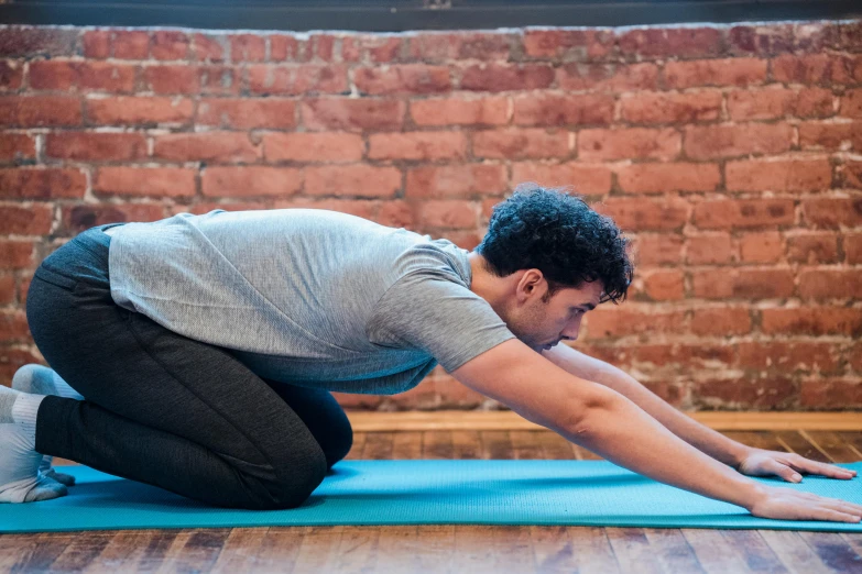 a man stretches on a yoga mat in front of a brick wall, by Rachel Reckitt, profile image, background image, david nakayama, central hub