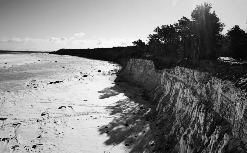 a black and white photo of a beach, by Karl Pümpin, between sedimentary deposits, winter sun, ravine, high quality upload