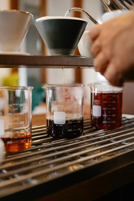 a close up of a person pouring liquid into a cup, beakers full of liquid, waxed, high samples, coffee smell