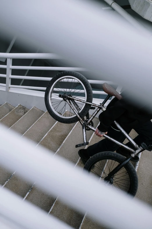 a man riding a bike down a flight of stairs, pexels contest winner, realism, low quality footage, stainless steel, resting, whips