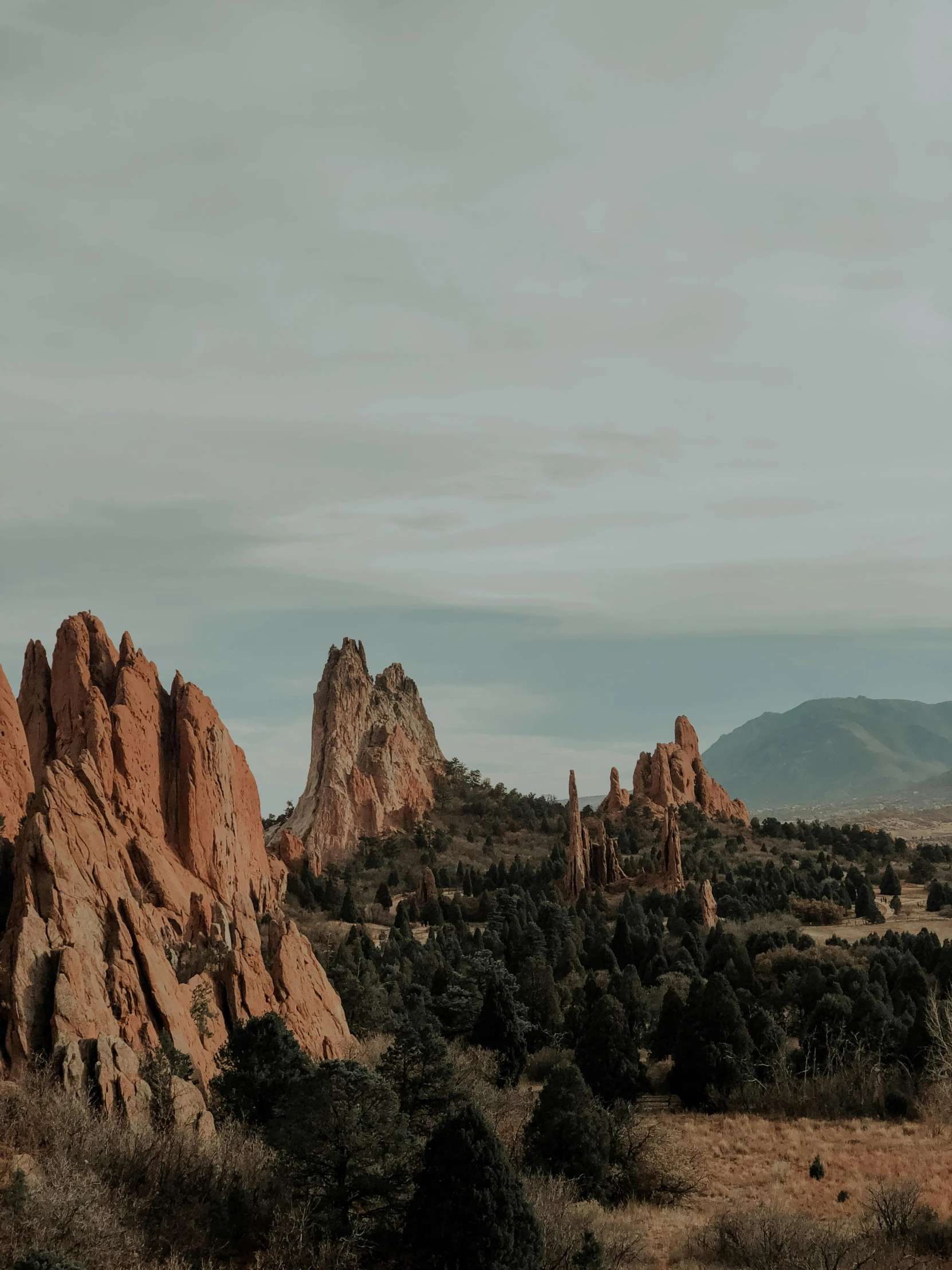 a couple standing on top of a lush green field, by Kyle Lambert, unsplash contest winner, renaissance, tall stone spires, red sandstone natural sculptures, moody : : wes anderson, colorado