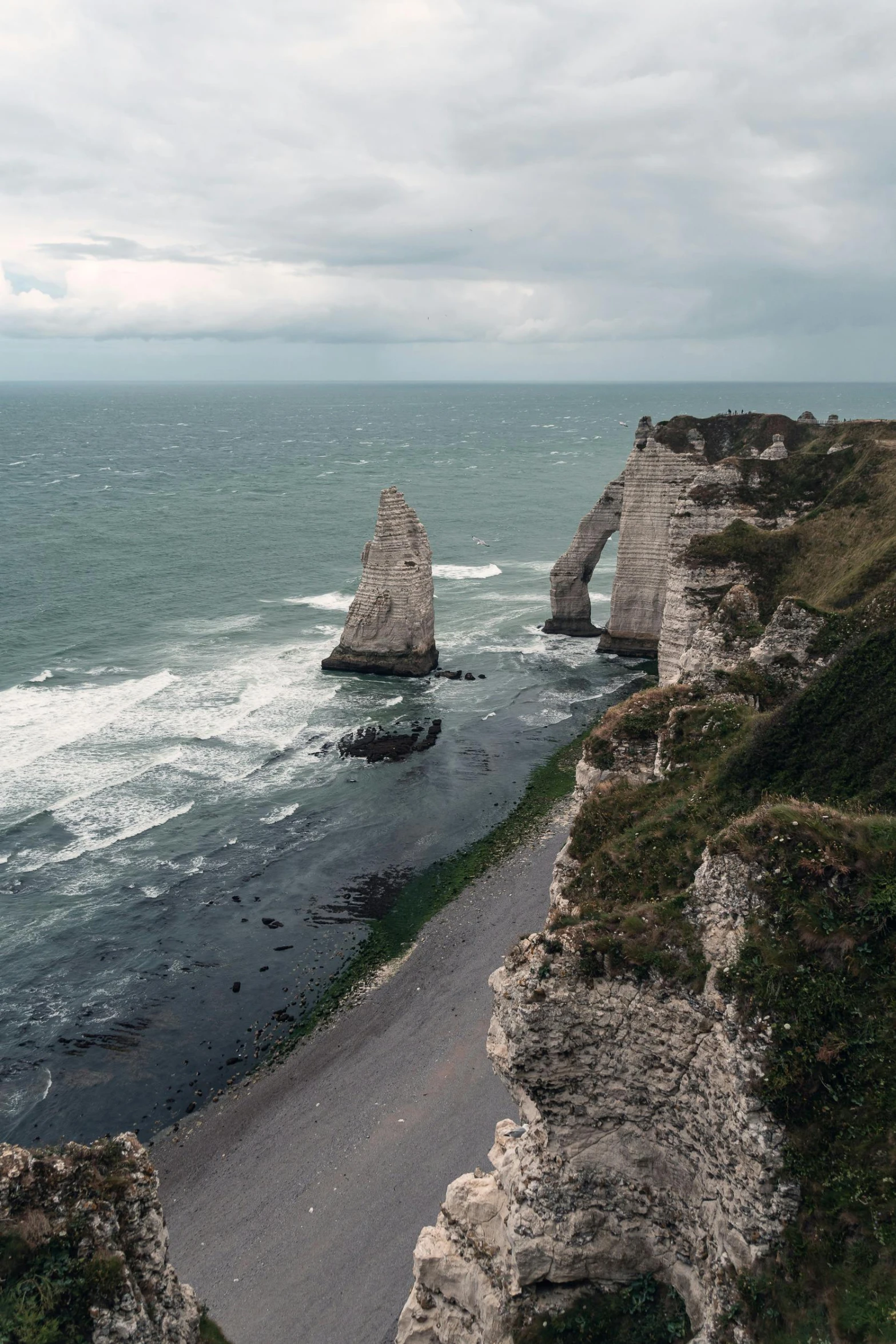 a man standing on top of a cliff next to the ocean, les nabis, tall stone spires, omaha beach, road trip, gigapixel photo