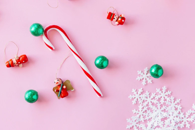 a candy cane surrounded by christmas ornaments on a pink background, by Julia Pishtar, trending on pexels, background image, modelling, cute photo, sweets