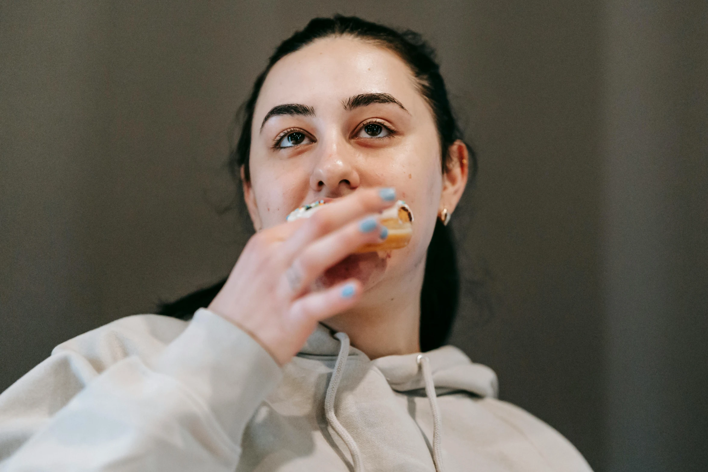 a woman eating a donut while wearing a hoodie, inspired by Sarah Lucas, trending on pexels, hyperrealism, glass and gold pipes, manuka, syd, underbite