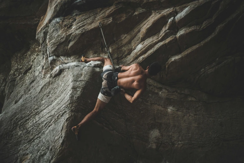 a man on a rock climbing up the side of a cliff, pexels contest winner, figuration libre, shirtless, indoor picture, grey, set photo