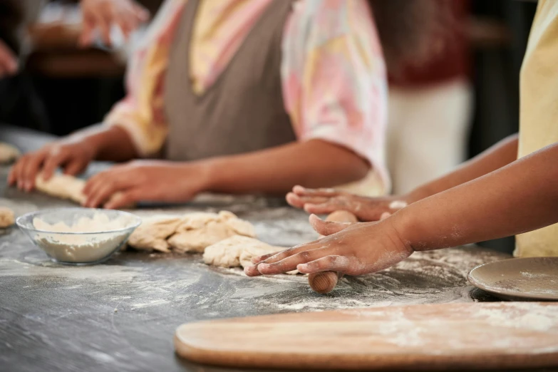 a group of people knead dough on a table, by Jessie Algie, trending on pexels, process art, aboriginal, kids playing, closeup at the food, head to waist