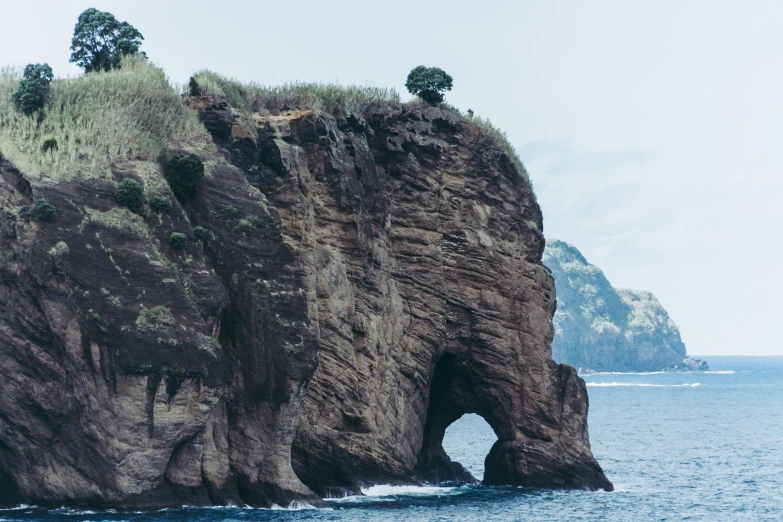 a large rock formation in the middle of a body of water, azores, an archway, indonesia, instagram post