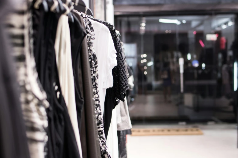 a rack of clothes in a clothing store, by Nina Hamnett, unsplash, wearing black modern clothes, federation clothing, profile image, white and black