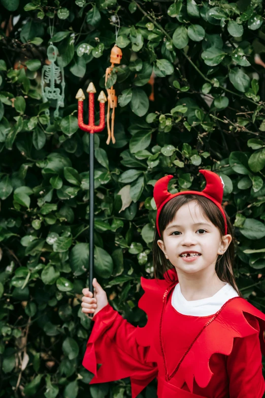 a little girl dressed in a red devil costume, pexels contest winner, holding the elder wand, full product shot, pitchburn devils!, little