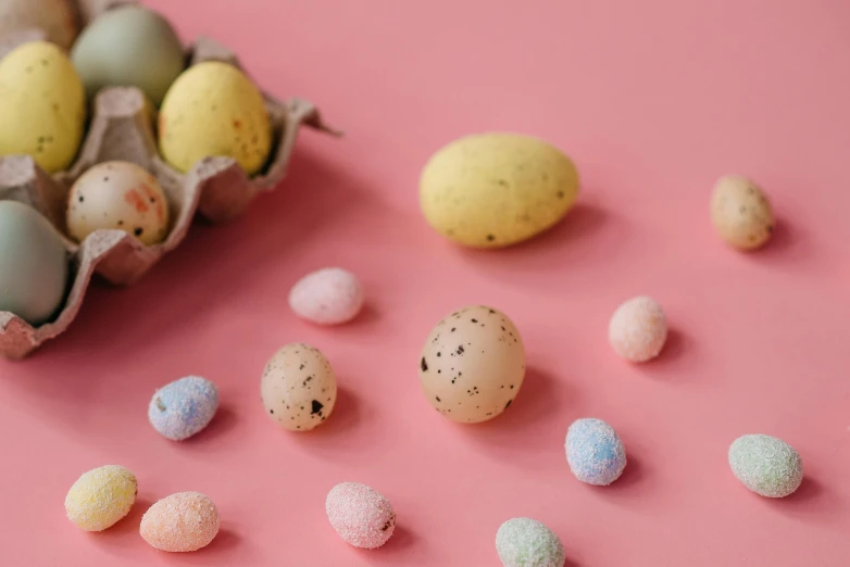 a carton of eggs sitting on top of a pink surface, by Sylvia Wishart, trending on pexels, candy decorations, coral-like pebbles, thumbnail, mid - shot