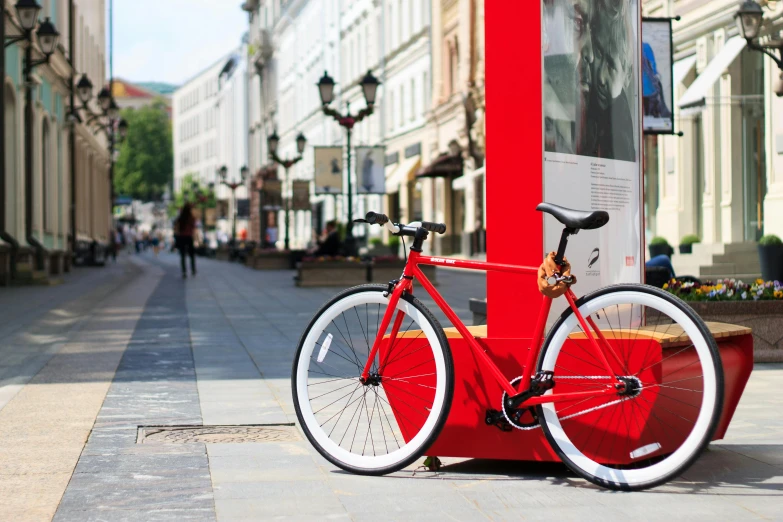 a red bicycle chained to a pole on a city street, pexels contest winner, square, white red