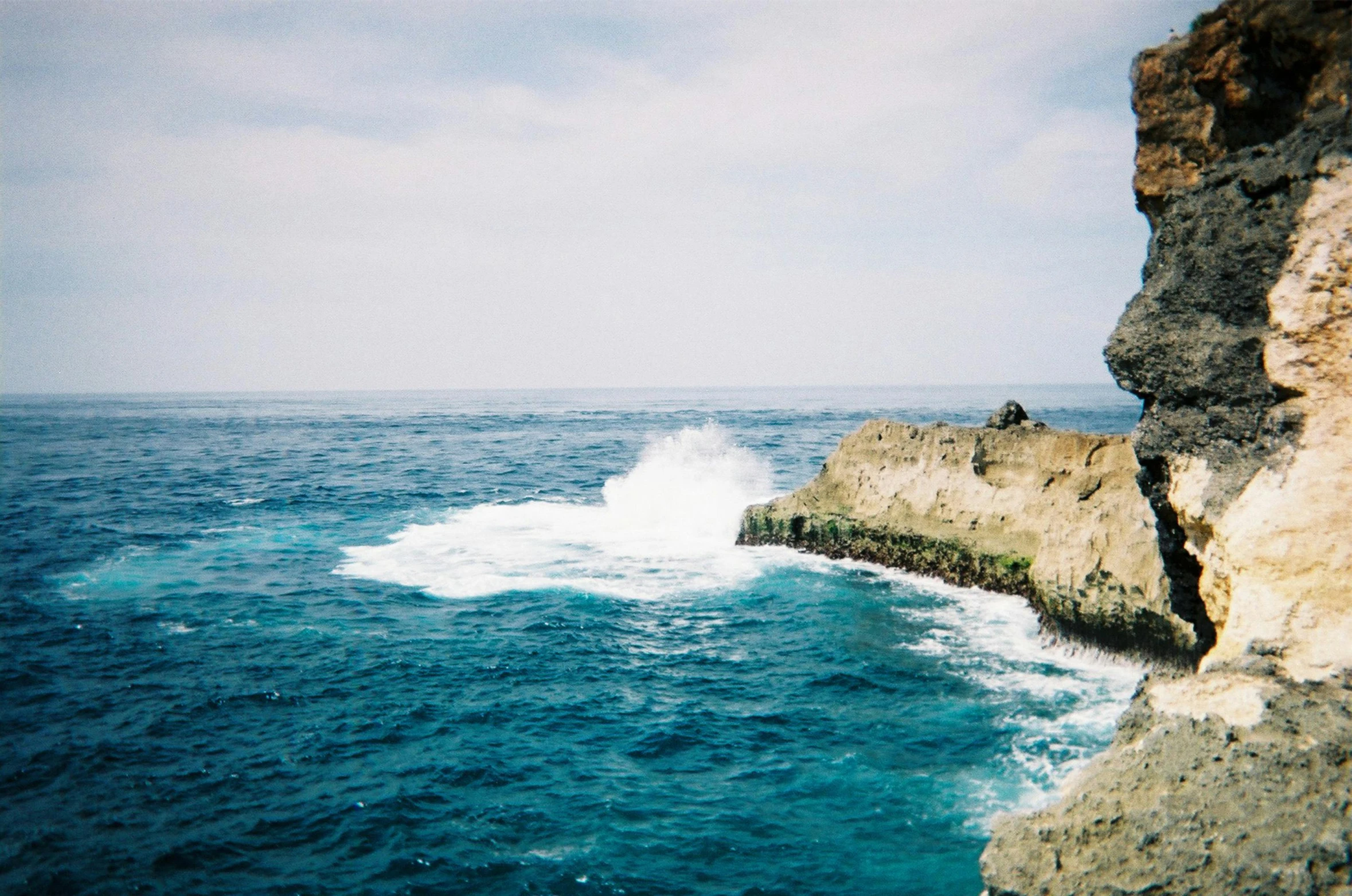 a man standing on top of a cliff next to the ocean, les nabis, medium format photography, rinko kawauchi, blue, splashing