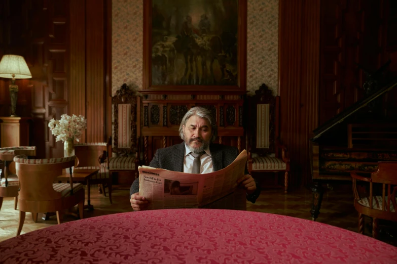 a man sitting at a table reading a book, an album cover, baroque, slavoj zizek, in their noble mansion, newspaper photography, shot with sony alpha 1 camera