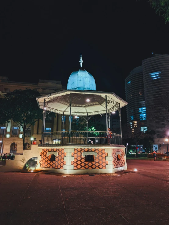 a gazebo in the middle of a city at night, a colorized photo, unsplash contest winner, malaysian, profile image, tiled fountains, wellington